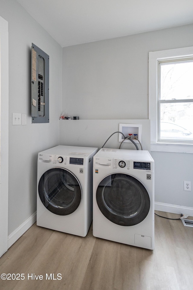 washroom with electric panel, laundry area, washer and clothes dryer, and wood finished floors