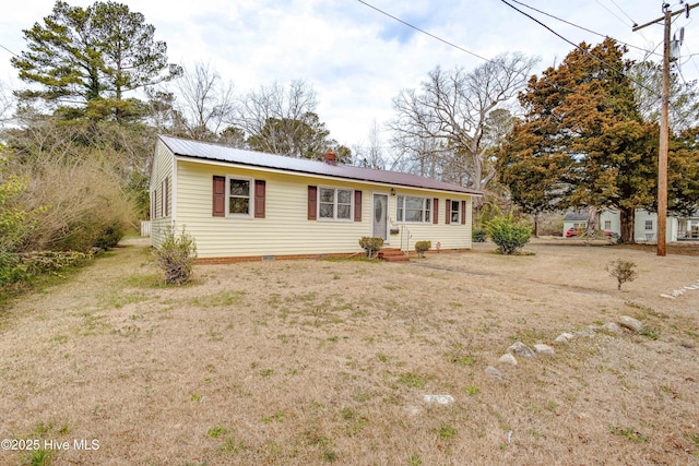 ranch-style home with entry steps, metal roof, and a front lawn