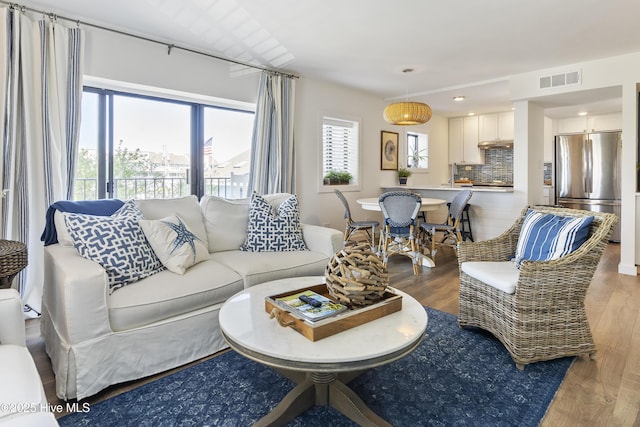 living area featuring a wealth of natural light, visible vents, and light wood finished floors