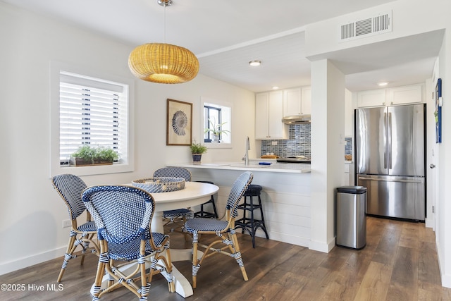 dining area featuring dark wood-type flooring, a healthy amount of sunlight, and visible vents