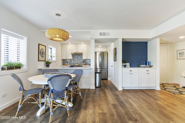 dining space with visible vents, baseboards, and dark wood finished floors