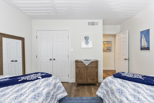 bedroom with dark wood finished floors, baseboards, visible vents, and a closet