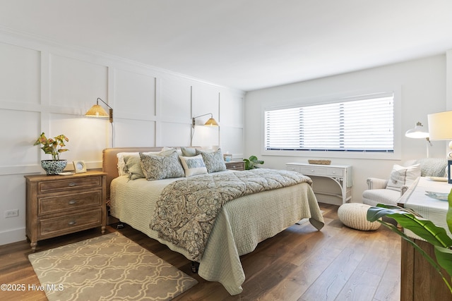 bedroom with dark wood-style flooring and a decorative wall