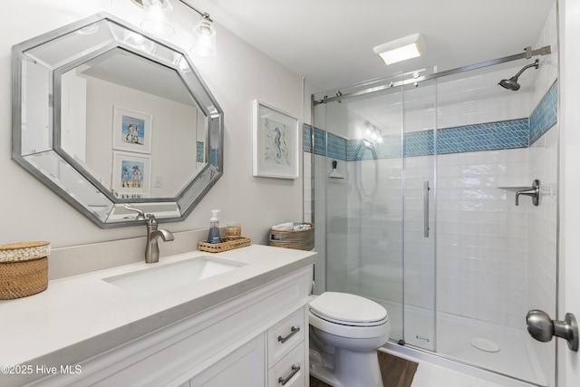 full bathroom featuring vanity, wood finished floors, a shower stall, and toilet