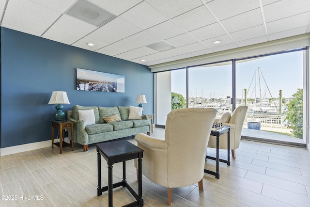 living area featuring baseboards and a paneled ceiling