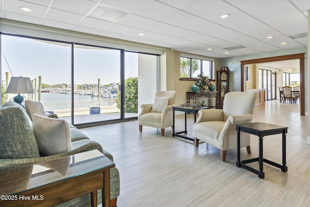 living room featuring a drop ceiling, recessed lighting, and a water view