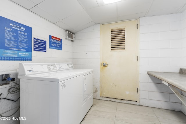 clothes washing area with laundry area, concrete block wall, light tile patterned floors, and washing machine and clothes dryer