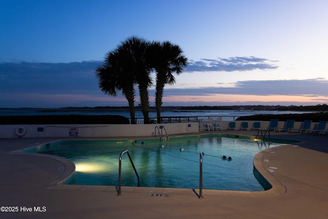 pool at dusk featuring a community pool and a patio area