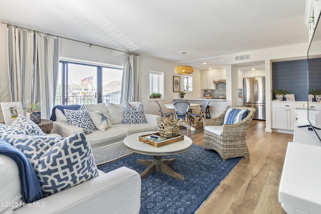 living area featuring light wood finished floors and visible vents