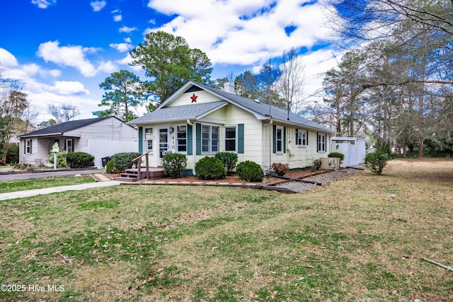 ranch-style home featuring a chimney, a front lawn, and roof with shingles