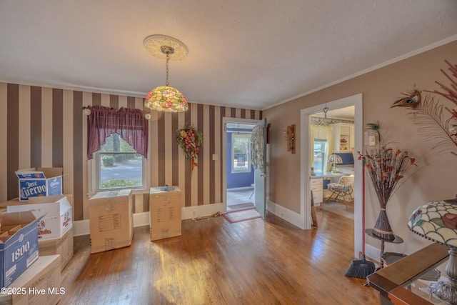 dining room featuring wallpapered walls, wood finished floors, baseboards, and ornamental molding