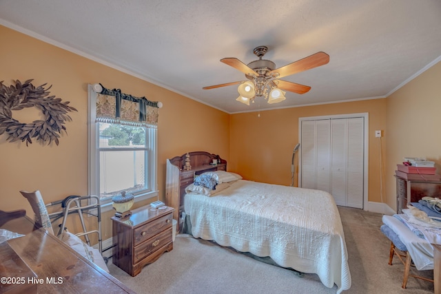 carpeted bedroom featuring a closet, baseboards, ceiling fan, and ornamental molding