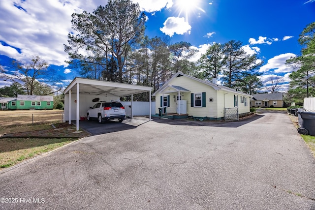 view of front of home featuring aphalt driveway, a carport, and fence