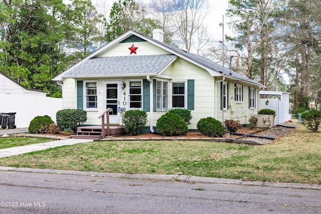 bungalow-style house featuring a front yard, fence, a chimney, and a shingled roof