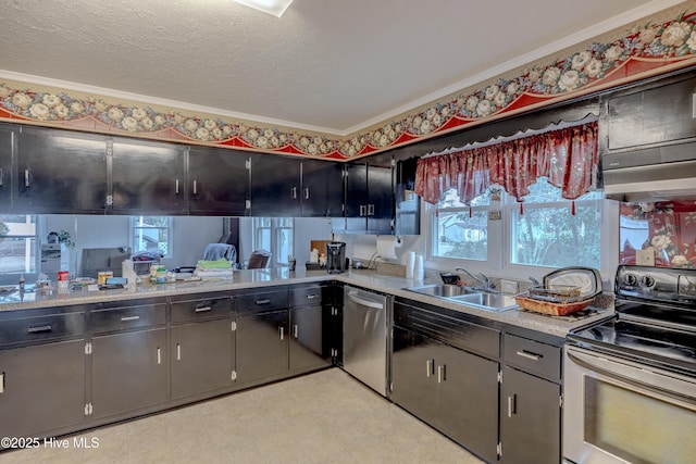 kitchen with a sink, a textured ceiling, stainless steel appliances, light countertops, and light floors