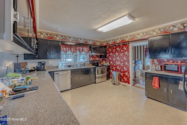 kitchen with a textured ceiling, stainless steel appliances, light floors, and wallpapered walls