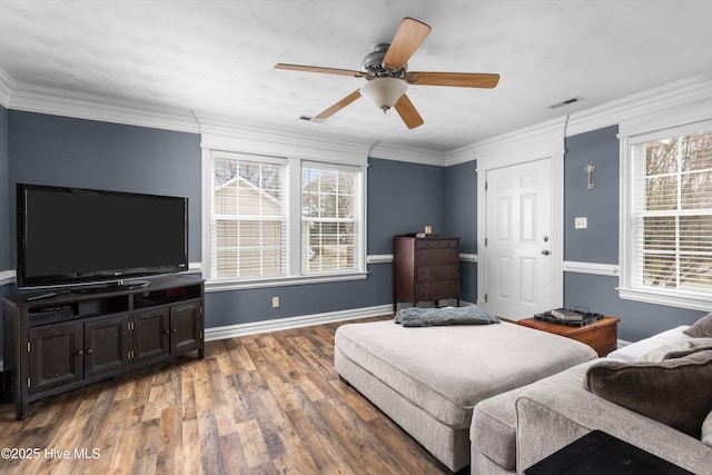 living area with visible vents, wood finished floors, and ornamental molding