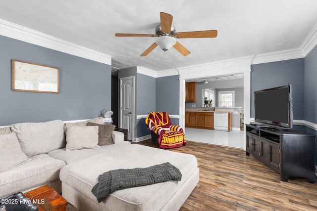 living area with ceiling fan, baseboards, wood finished floors, and crown molding