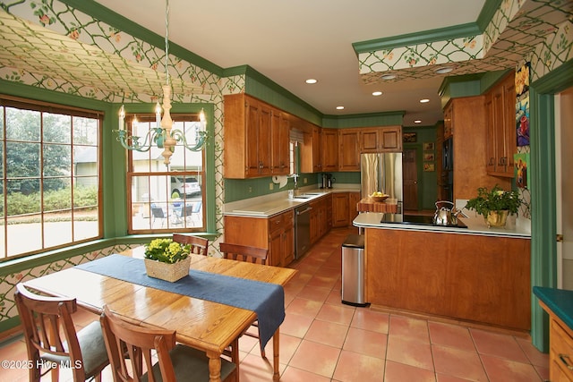 kitchen featuring wallpapered walls, brown cabinetry, a notable chandelier, stainless steel appliances, and a sink