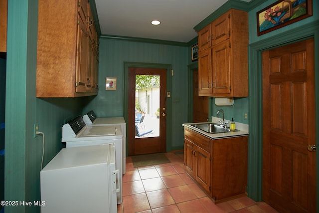 washroom with light tile patterned floors, washing machine and clothes dryer, cabinet space, a sink, and crown molding