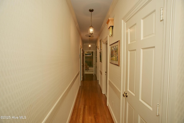 corridor featuring baseboards, dark wood-type flooring, and ornamental molding