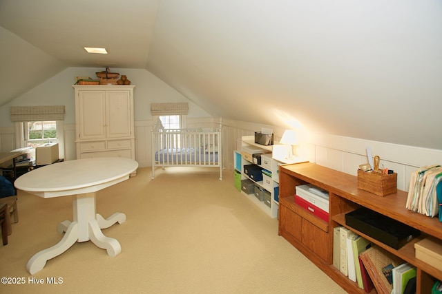 interior space with wainscoting, light colored carpet, and vaulted ceiling