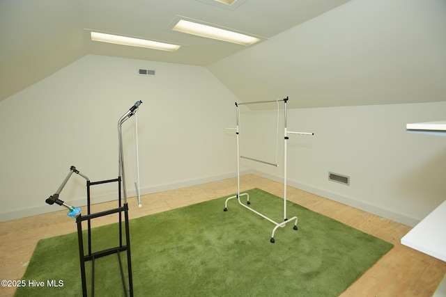 exercise area with visible vents, lofted ceiling, and baseboards