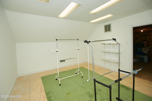 workout area with visible vents, baseboards, light wood-type flooring, and lofted ceiling