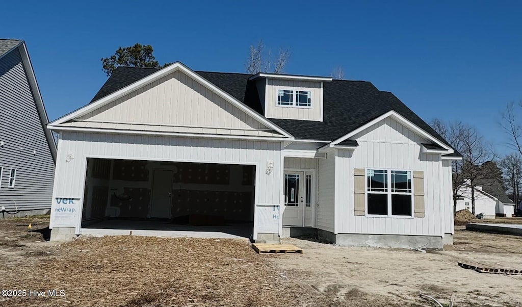 modern inspired farmhouse with an attached garage and roof with shingles