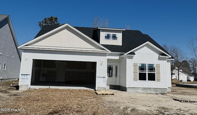 modern inspired farmhouse with an attached garage and roof with shingles