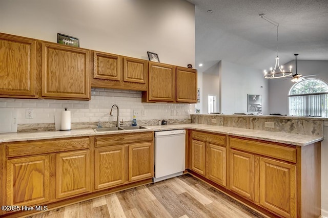 kitchen with a sink, a peninsula, light wood finished floors, lofted ceiling, and dishwasher