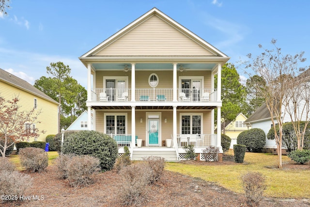 greek revival inspired property with a balcony, covered porch, a front lawn, and ceiling fan