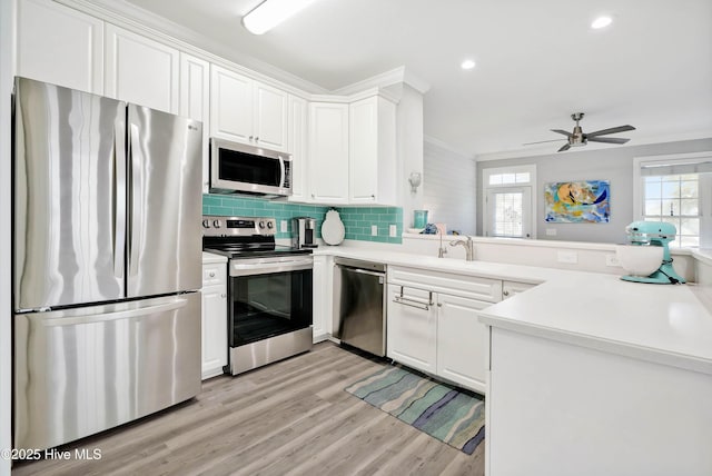 kitchen with stainless steel appliances, light wood-style floors, a healthy amount of sunlight, and crown molding