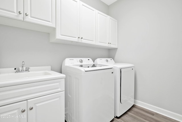 laundry room featuring baseboards, light wood finished floors, cabinet space, a sink, and washer and dryer