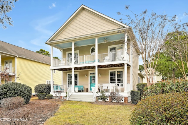 view of front of property featuring a balcony, covered porch, ceiling fan, and a front yard