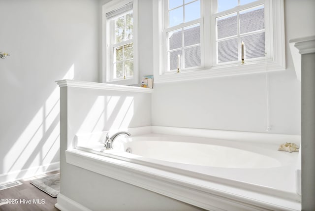 bathroom with a garden tub, wood finished floors, and visible vents