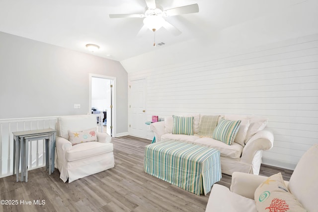 living area featuring visible vents, ceiling fan, baseboards, lofted ceiling, and wood finished floors