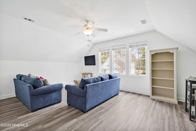 living room featuring vaulted ceiling, visible vents, baseboards, and wood finished floors