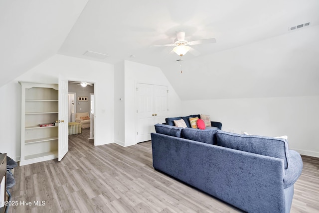 living area featuring lofted ceiling, wood finished floors, visible vents, and baseboards