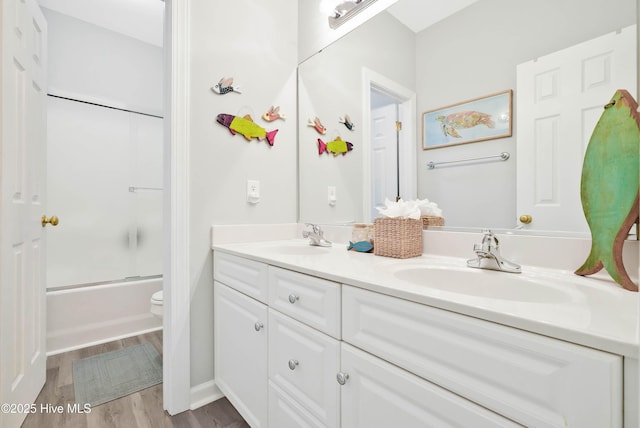 full bathroom with a sink, toilet, wood finished floors, and double vanity