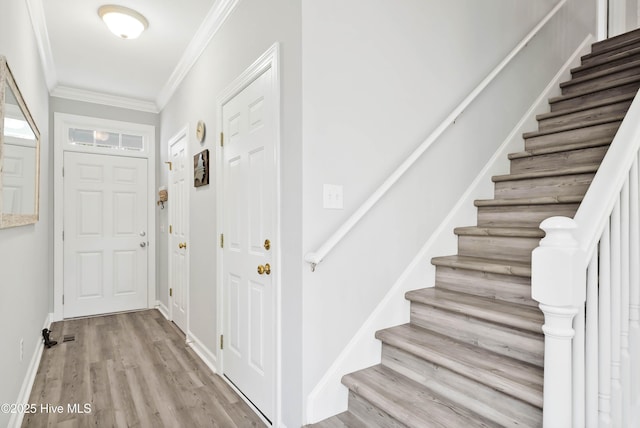 entrance foyer with stairs, baseboards, light wood-style floors, and crown molding