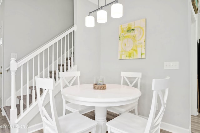 dining area featuring stairs, baseboards, and wood finished floors