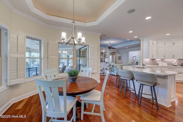 2184 Villamar Dr, Leland, NC 28451 - dining space with light wood-style flooring, ornamental molding, ceiling fan with notable chandelier, a tray ceiling, and baseboards