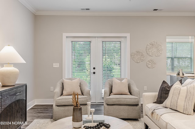 living area with a wealth of natural light, visible vents, wood finished floors, and crown molding