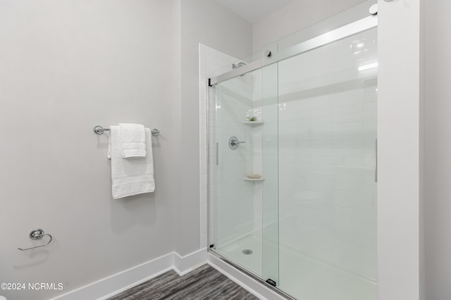 bathroom featuring baseboards, wood finished floors, and a shower stall