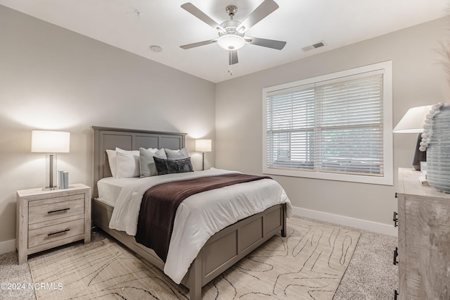 bedroom featuring light colored carpet, baseboards, visible vents, and a ceiling fan