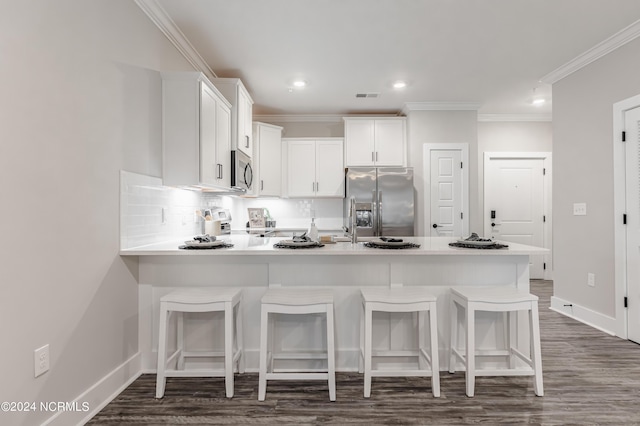 kitchen with visible vents, a peninsula, stainless steel appliances, and crown molding