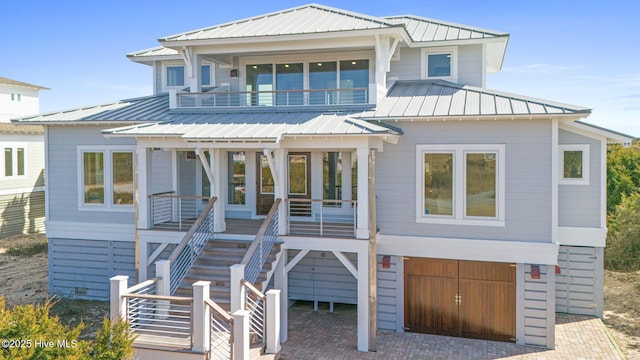 beach home featuring a standing seam roof, stairway, decorative driveway, and metal roof