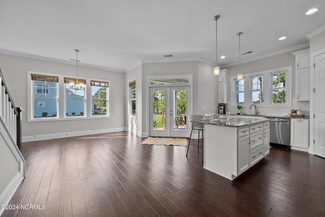 kitchen featuring dark wood finished floors, a sink, decorative backsplash, dishwasher, and a kitchen bar