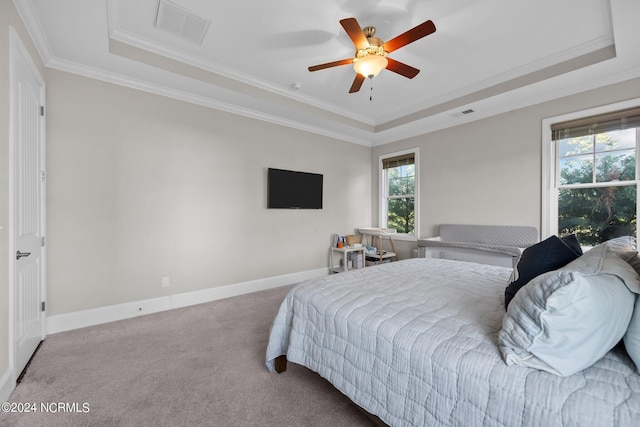 carpeted bedroom with visible vents, a raised ceiling, baseboards, and crown molding